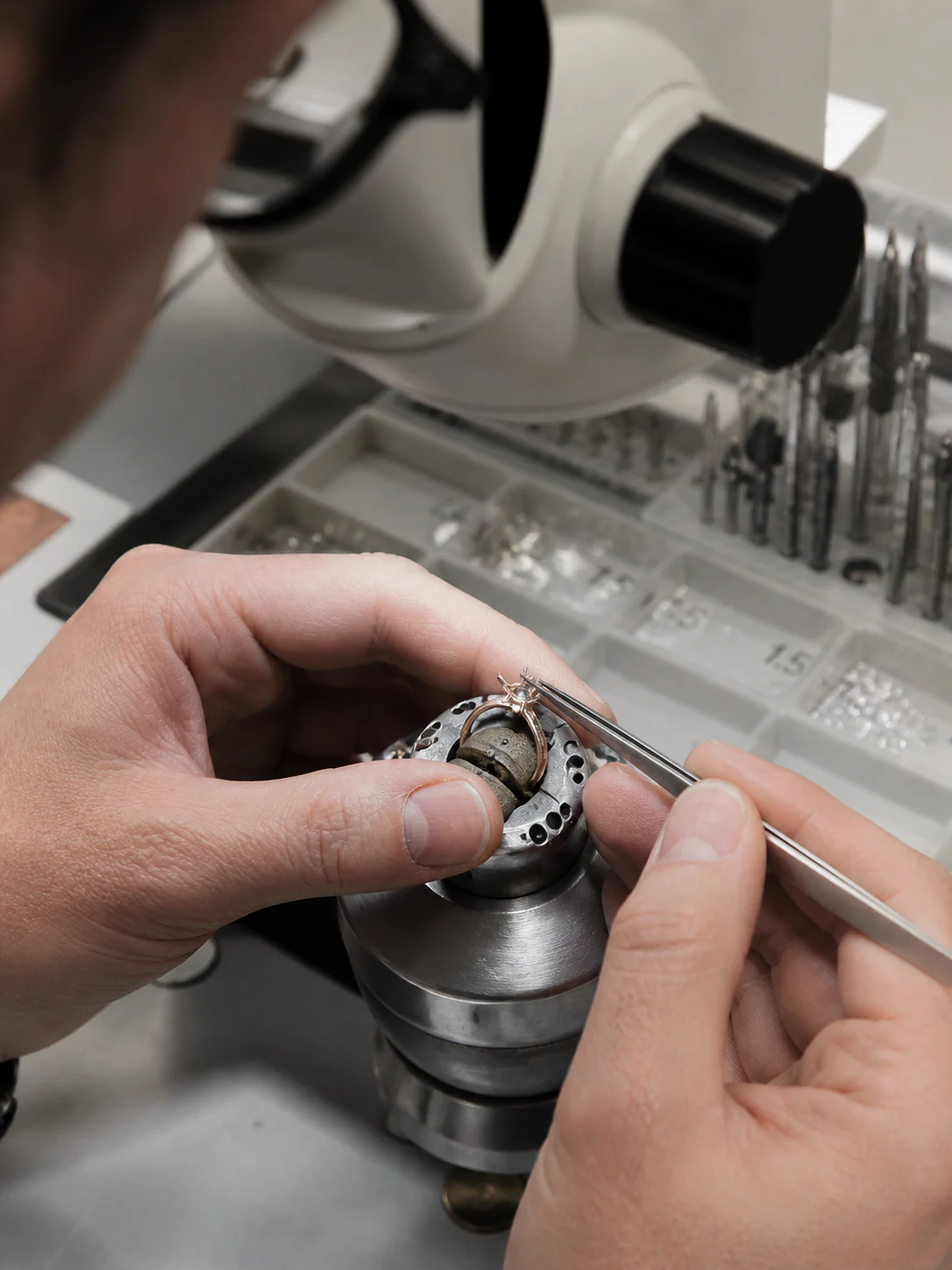 Jeweler crafting a ring with tweezers under magnification