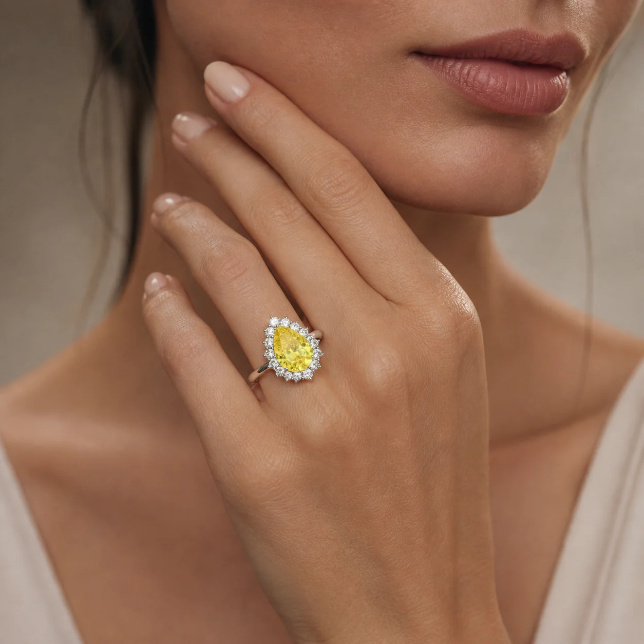 Yellow pear-shaped centre stone ring framed by a brilliant halo on the hand