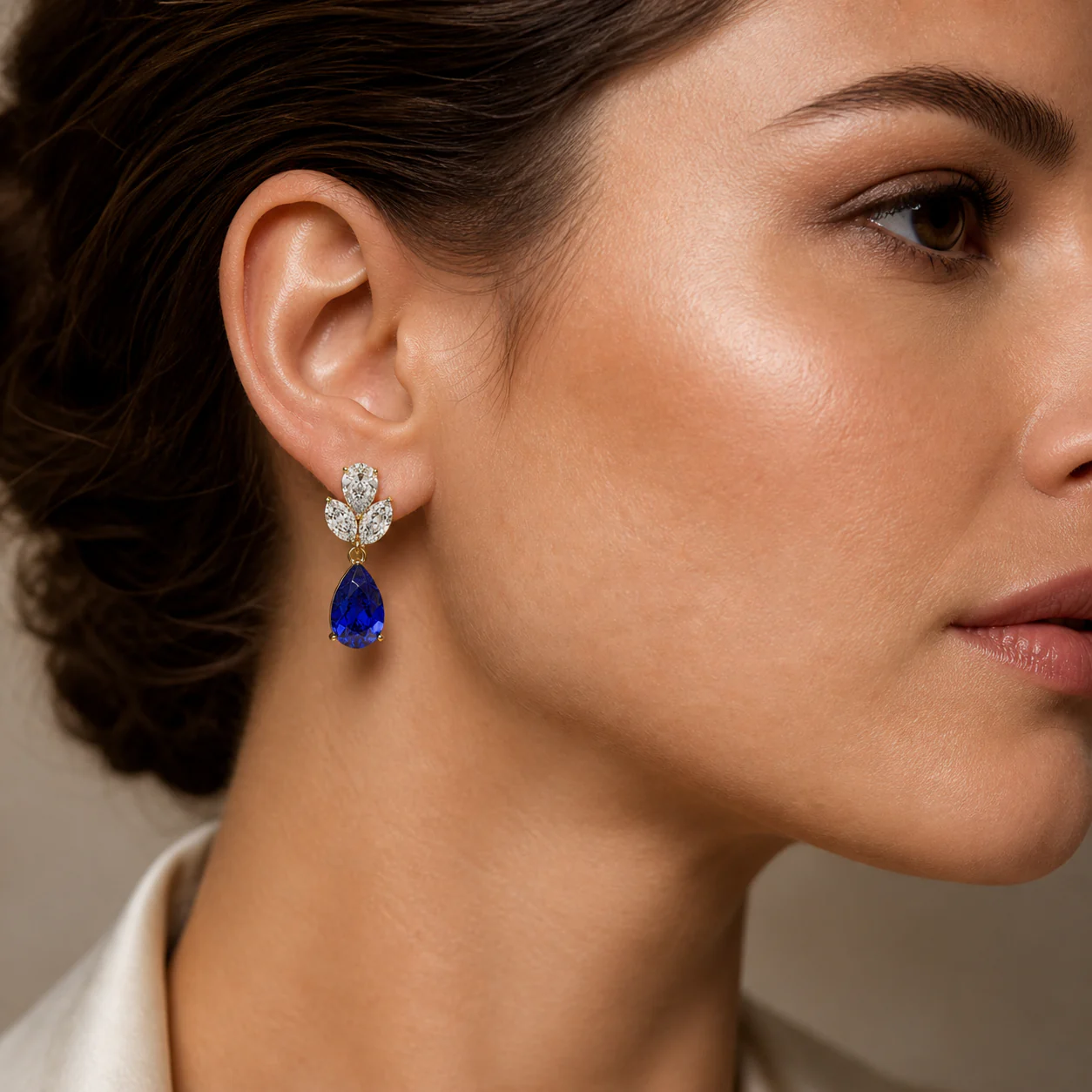 Blue drop earrings with luminous white stones and a deep blue pear-shaped accent worn close to the face